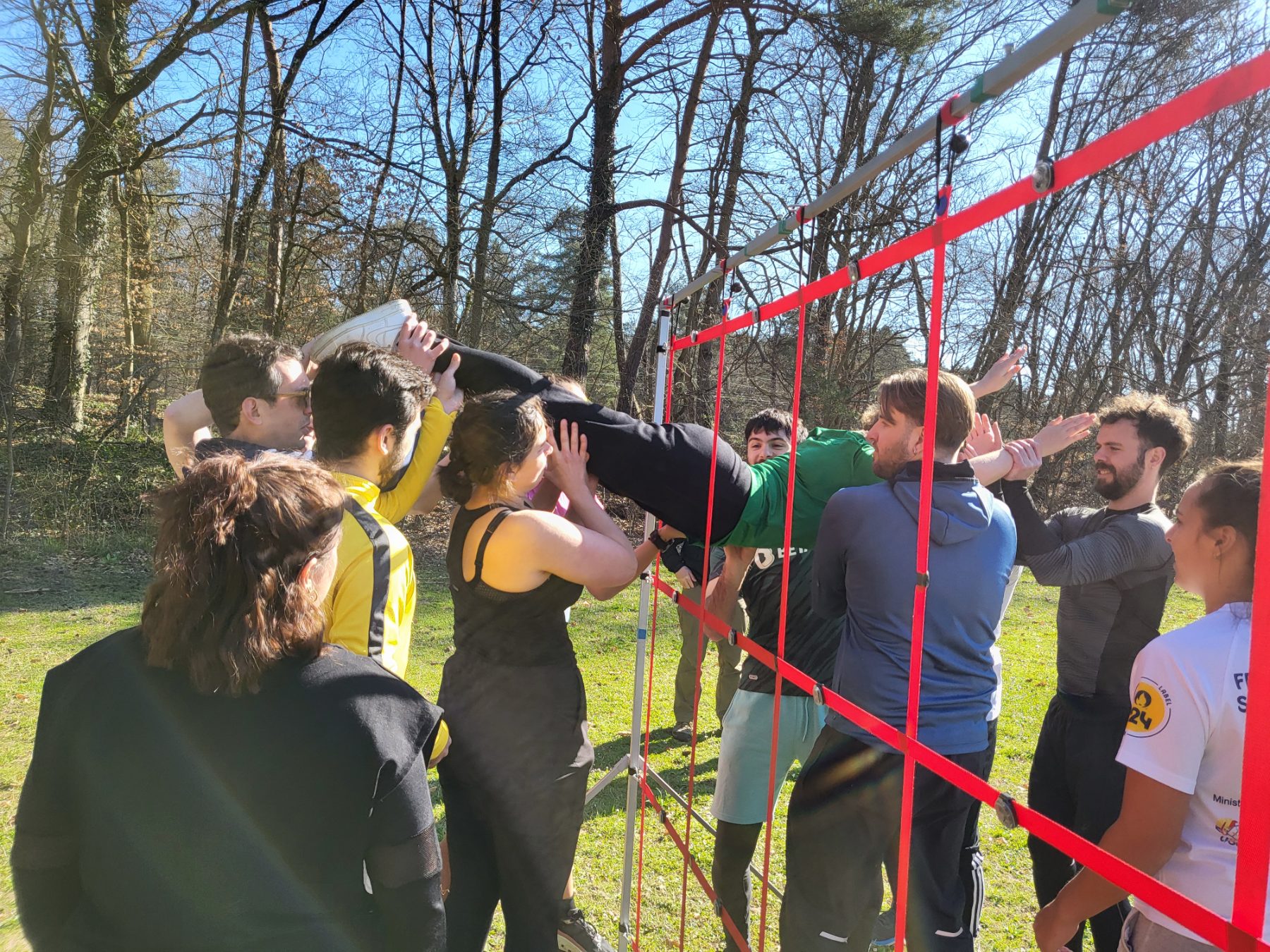 Une équipe fait passer l'un des siens à travers une toile de cordes